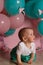 little girl sitting on the floor in the room next to the balloons, first birthday, celebrate. one year old blue and pink balls wit