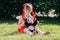 a little girl sitting on the grass in a park with a toy bear panda