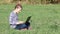 Little girl sitting on grass and playing laptop