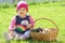 Little girl sitting in green grass with three kittens in basket