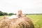 Little girl is sitting on a haystack, a summer concept