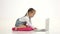 Little girl is sitting on her lap and looking at the laptop. White background