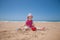 Little girl sitting making a castle in sand beach