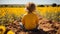 a little girl sitting in the middle of a field of sunflowers
