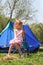 Little girl sitting near tent on nature