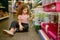 Little girl sitting on pet shop floor nearby cage with rodent