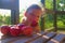 Little girl is sitting on porch in summer. Small girl is eating apples. Apples on table. Dreamy and romantic image