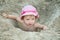 Little girl sitting in a sand hole