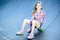 Little girl sitting on a skateboard, skatepark on the street