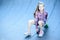 Little girl sitting on a skateboard, skatepark on the street