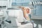 Little girl sitting in stomatology clinic chair and smiling at mirror showing her teeth after teeth dental procedures. Healthcare