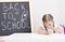 A little girl is sitting at a table with her hand over her face. School