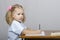 Little girl sitting at the table and wrote in a notebook. View the profile