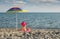 Little girl with sitting under sunshade on beach