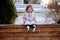 Little girl sitting on wooden planks and reading the bible in a garden covered in the snow