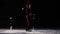 A little girl skater in a black sports suit and white skates performs a spinning stand in the arena of the ice stadium