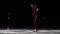 A little girl skater in a black sports suit and white skates performs a spinning stand in the arena of the ice stadium