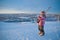 Little girl-skier on the hill watching the sunrise