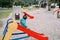 Little girl slides down a colorful slide in the playground. Side view