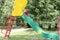 A little girl slides down a slide on an outdoor Playground in summer.