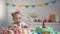 Little girl slowly appearing from under table and admiring colorful Easter eggs