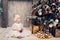 Little girl in a smart dress sits near a Christmas tree