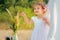 Little girl smiles and shows finger upward. A girl in a white Wigwam or play tent, children`s play house