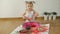 Little girl with smudgy paint fingers draws on a large sheet of white paper sitting on the floor