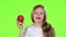 Little girl sniffs and bites an apple. Green screen. Slow motion