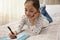 Little girl solving sudoku puzzle on bed