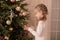 Little girl spends time decorating the Christmas tree. Preparing for the holidays. Santa will be glad