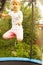 A little girl in sportswear jumps on a trampoline in the garden.