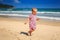 Little Girl in Spotty Dress Runs by Shallow Wave Surf on Beach