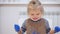 A little girl stained her hands and clothes in paint while drawing. The child carefully examines the dirty hands.