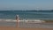 A little girl standing on at the adge of a sea and looking at the water