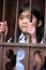 Little girl standing behind iron bars