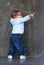 Little girl is standing being hold the marble wall and pointing to the side with her index finger