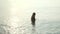 Little girl standing in evening sea. Girl washing mask for diving in sea