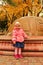 Little girl standing near fountain in autumn