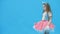 LIttle girl standing over blue background in 4k slowmotion video.