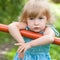 Little girl standing thoughtfully on a bench closeup face view