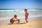 Little Girl Stands and Boy Squats on Edge of Wave Surf