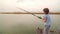 a little girl stands with a fishing rod on a bridge by the river.