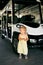 Little girl stands near a six-seater golf cart in the parking lot