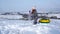 A little girl stands near the tube and plays with her sister with snow