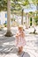 Little girl stands on the patio and chews on a bottle of water