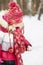 Little girl stands in winter park holding artificial bird