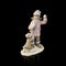 Little girl statuette in a pink jacket and hat is holding a snowball.