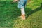 Little girl stepping on green grass barefoot