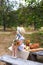 Little girl in straw hat with bouquet of flowers sits on bench on picnic in garden. Summer vacation. Copy space. Nature, healthy f